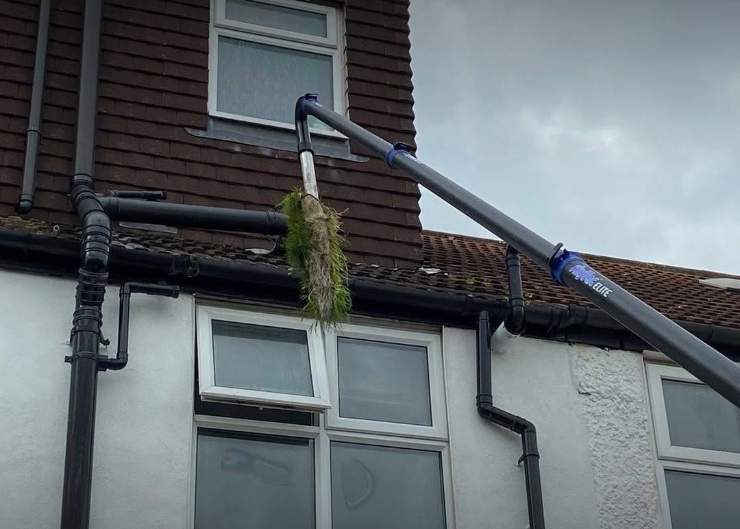 gutter-cleaning-epsom-vacuum GCS technician clearing moss from a gutter with a gutter vacuum pole, working from the ground